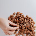 crop person taking almond nut from white table