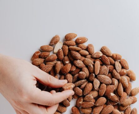 crop person taking almond nut from white table