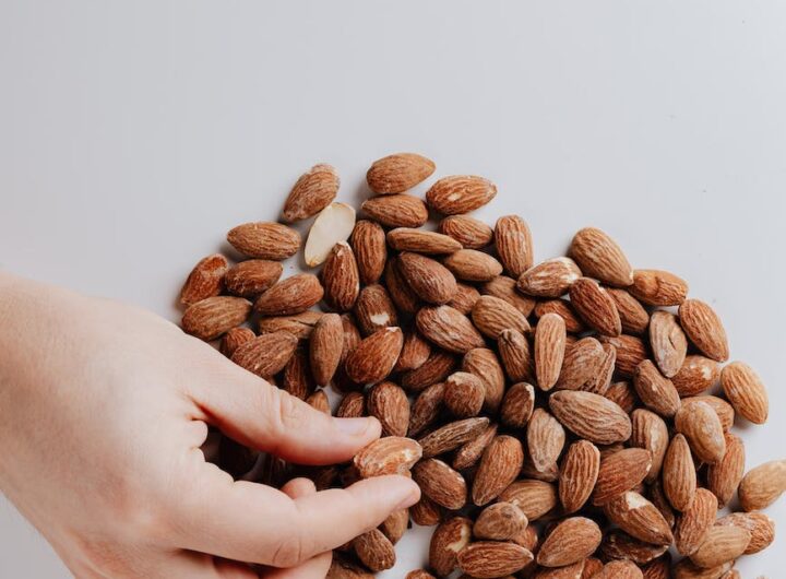 crop person taking almond nut from white table